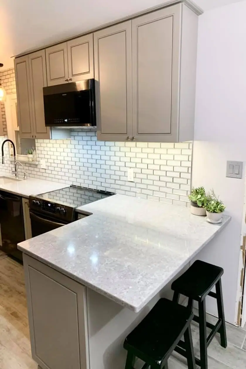 Gray shaker cabinets with white quartz countertops and a subway tile backsplash