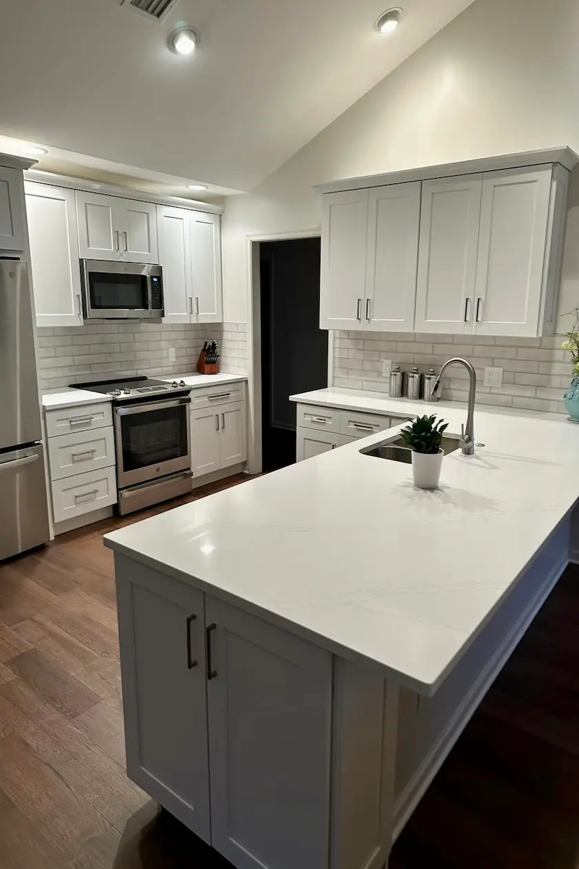 White upper cabinets with a gray island and white quartz countertops