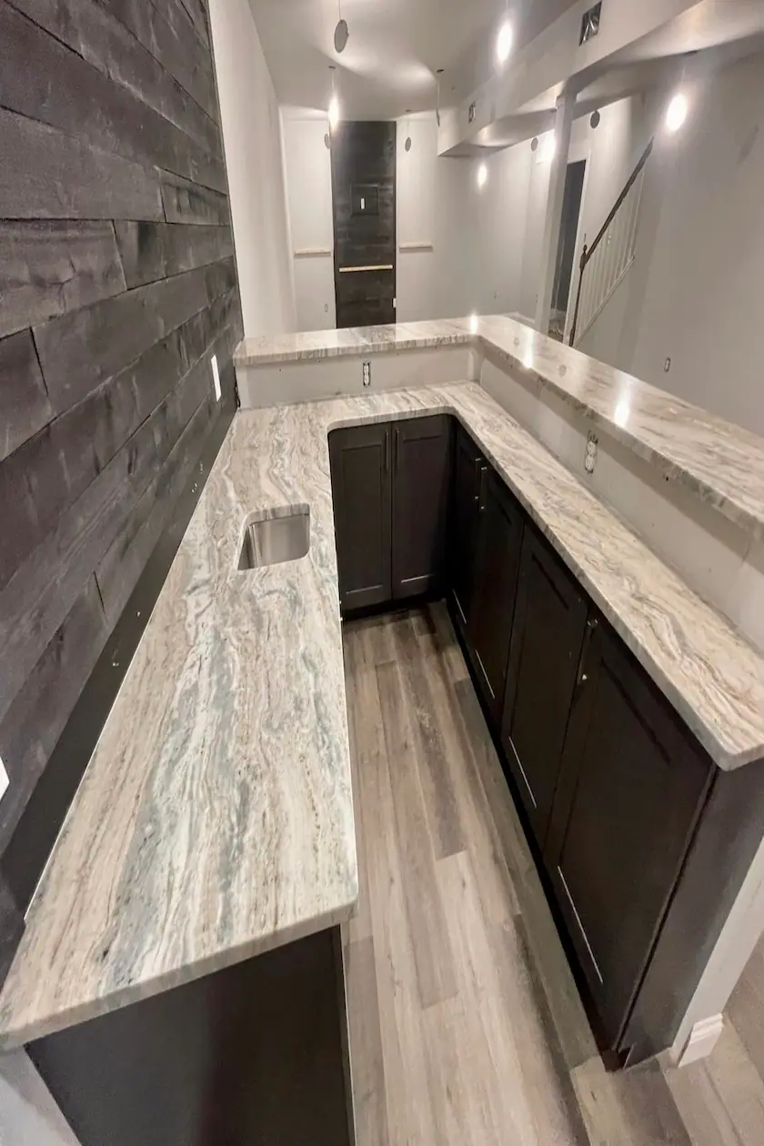Dark wood cabinets topped with a flowing marble-look countertop